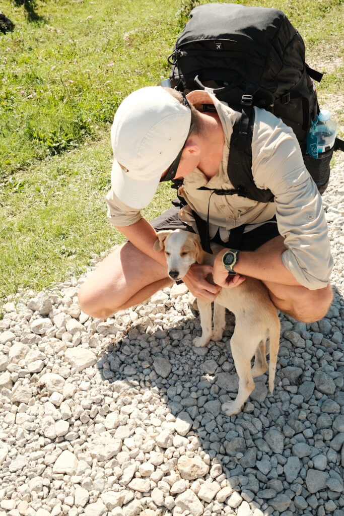 Riley patting a dog on the path to Theth