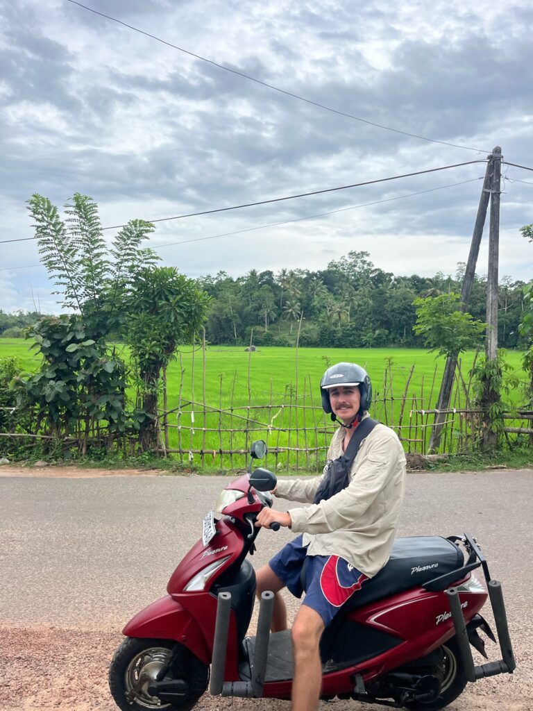 Riley sitting on a scoter next to rice fields